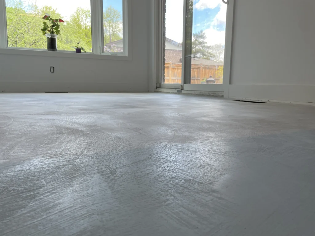 Smooth, newly finished micro-cement floor with natural light streaming through the windows.