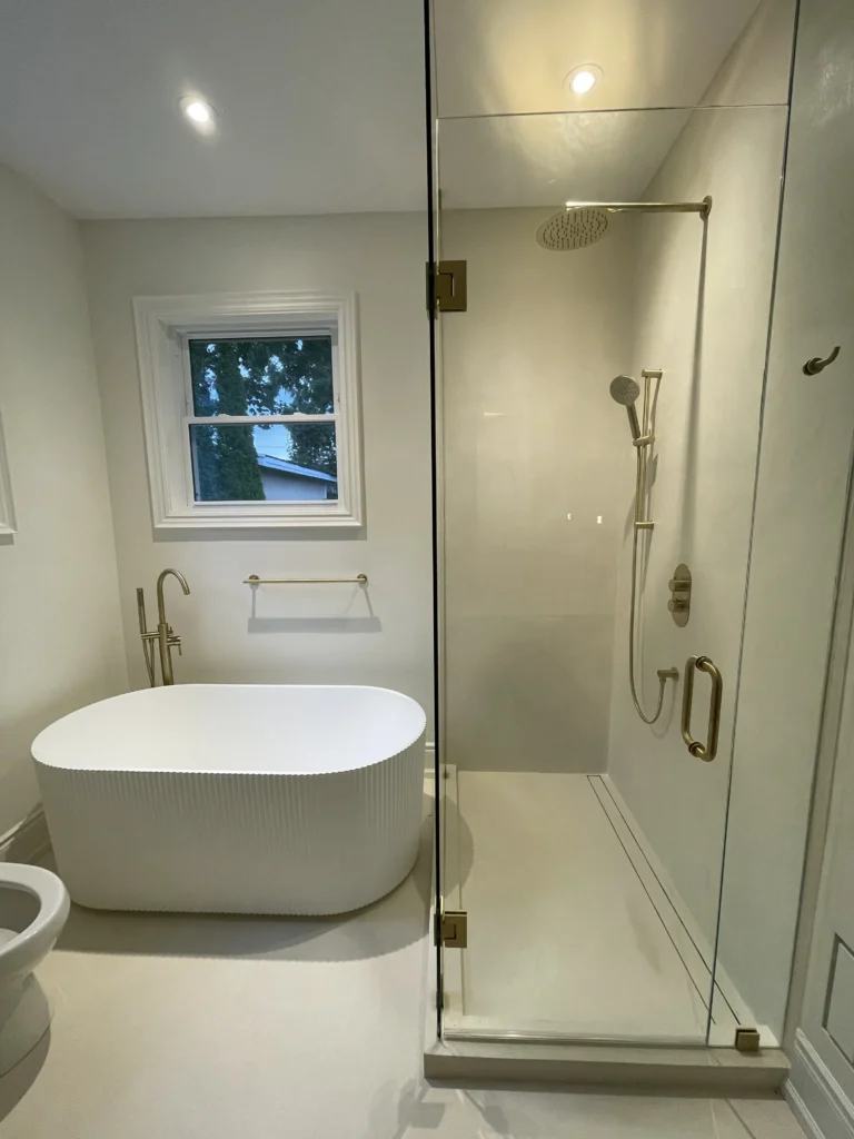 Minimalist bathroom with a freestanding bathtub, glass-enclosed shower, and brass fixtures.